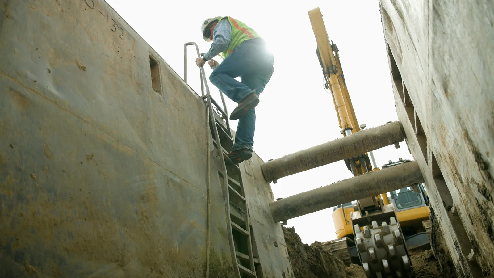 Excavator digging a utility trench on a road construction job